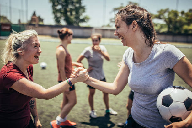 Women soccer players shaking hands Group of women, female soccer players together outdoors on soccer field, two women shaking hands. football player girlfriend stock pictures, royalty-free photos & images
