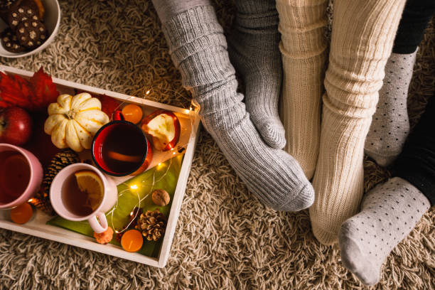 Lower section of three unrecognizable women in cozy sock enjoying warm tea Directly above shot of three unrecognizable young women sitting on the floor in their cozy socks and enjoying warm tea during cold autumn day. heat home interior comfortable human foot stock pictures, royalty-free photos & images