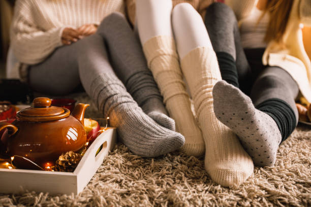 Enjoying warm tea in cozy sock on a cold autumn day Lower section of three unrecognizable young girlfriends sitting on the bedroom floor in their cozy socks and hanging out together while enjoying some warm tea on a cold autumn day. cozy stock pictures, royalty-free photos & images