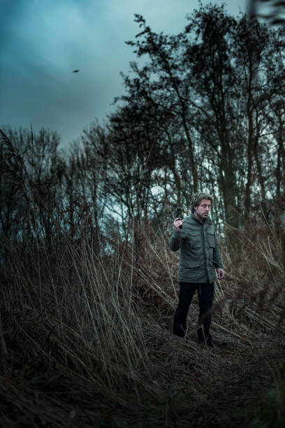 istock Man with pistol between reed on cloudy day. 1193258502