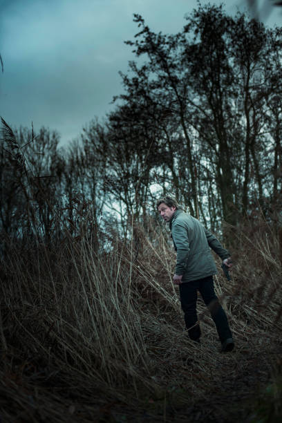 istock Man with pistol between reed on cloudy day. 1193259043