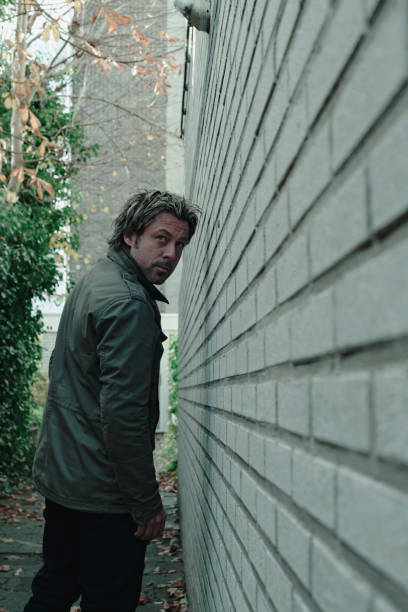 istock Man looking along white brick wall in alley. Rear view. 1193259113