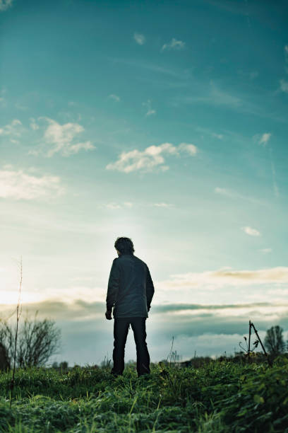 istock Mysterious man in rural landscape with cloudy sky at sunset. 1193259294