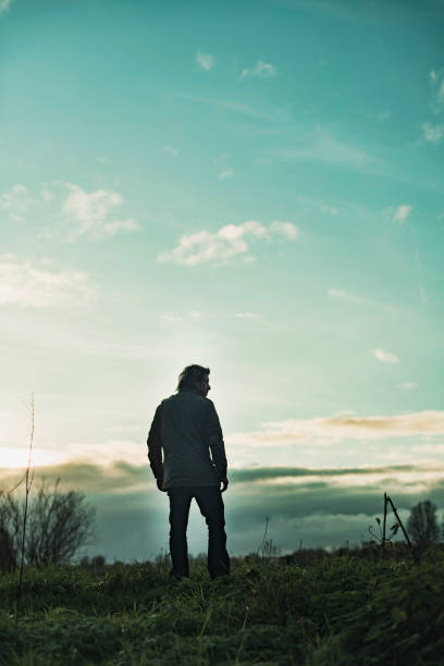 istock Mysterious man in rural landscape with cloudy sky at sunset. 1193259308