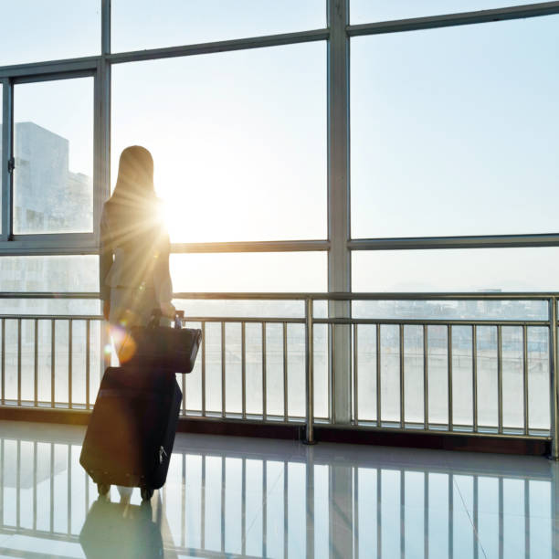 istock Businesswoman pulling a suitcase standing on entrance hall 1193259331
