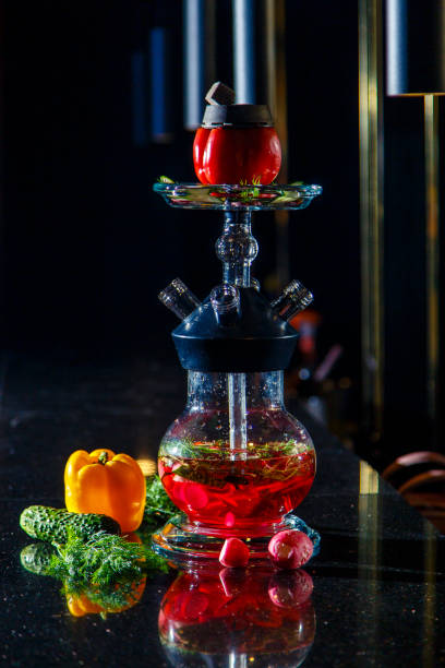 istock Hookah on vegetables. Hookah with a round transparent flask, which contains chopped vegetables: pepper, cucumber, radishes, herbs. Lots of smoke. 1193259721