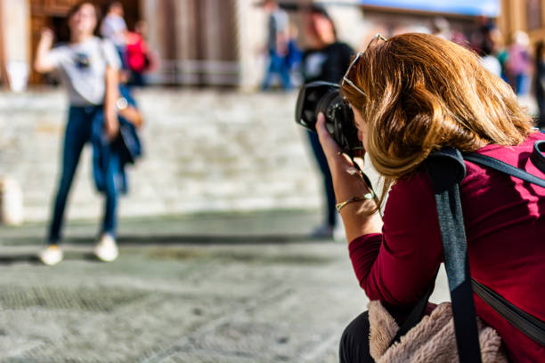 Young Photographer in the Action Young Male Tourist with Long Hair and Backpack is Photographing the Leaning Tower of Pisa During a Sunny Day. pisa leaning tower of pisa tower famous place stock pictures, royalty-free photos & images