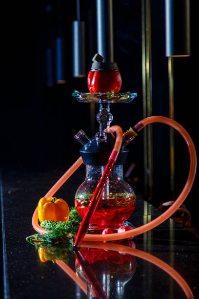istock Hookah on vegetables. Hookah with a round transparent flask, which contains chopped vegetables: pepper, cucumber, radishes, herbs. Lots of smoke. 1193261224