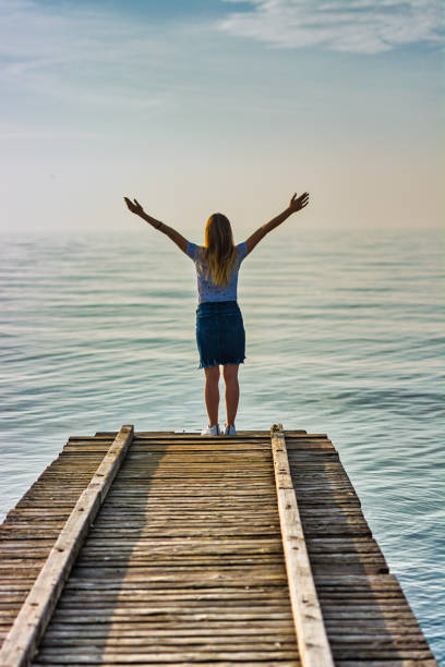 istock Woman Standing on a Ship Dock with Raised Arms 1193261822