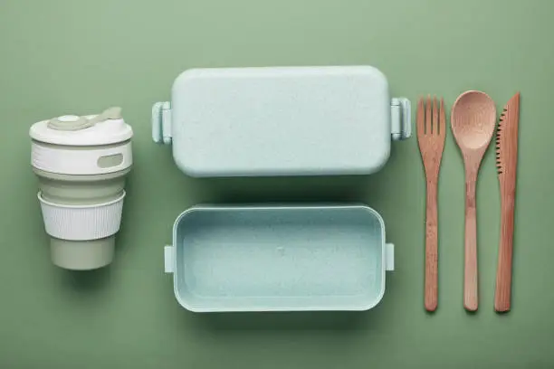 Zero waste lunch concept. Reusable cup and box, bamboo cutlery. Flat lay on green background