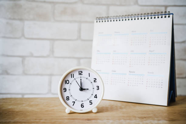 horloge analogique avec calendrier flou sur la table en bois - precise timing photos et images de collection