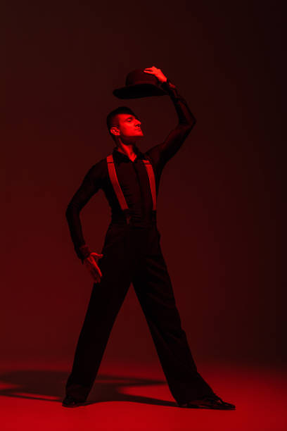 istock stylish dancer holding hat above head while performing tango on dark background with red lighting 1193267721