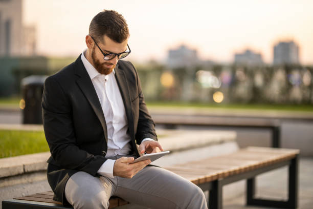 istock Businessman sitting on park bench and working 1193268794