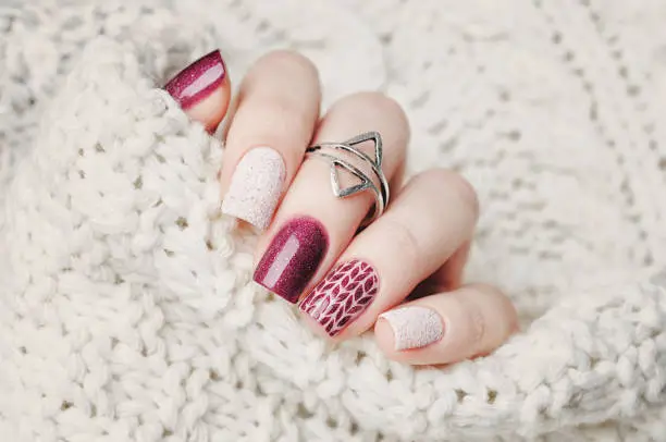 winter nail art manicure and knitted sweater on the background