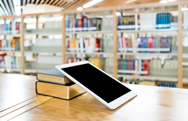 Digital tablet and books on the table of public library.