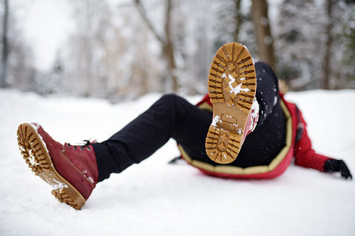 Shot of person during falling in snowy winter park. Woman slip on the icy path, fell and lies. Danger of season trauma.