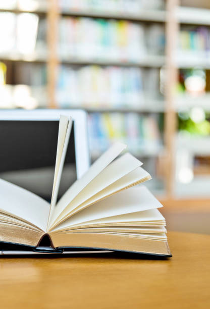 istock Laptop and open book on the table of public library 1193273616