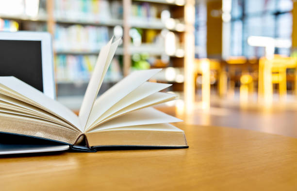 istock Laptop and open book on the table of public library 1193273768