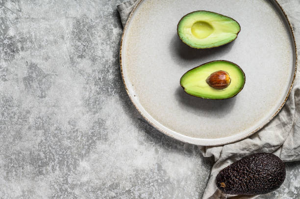 istock Ripe avocado halves on a clay plate. Gray background. Top view. Space for text 1193274582