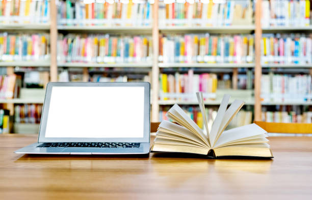 istock Laptop and open book on the table of public library 1193276137