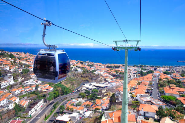 View from the cable car in Funchal from the seaside to Monte on Madeira Island Portugal View from the cable car from the seaside to Monte in Funchal, Madeira Island Portugal with a lovely aerial view over the city and sea. Tourists take this way of transport for the views over the city and to visit the botanical gardens in Monte as well as the traditional toboggan ride down the hill. funchal stock pictures, royalty-free photos & images