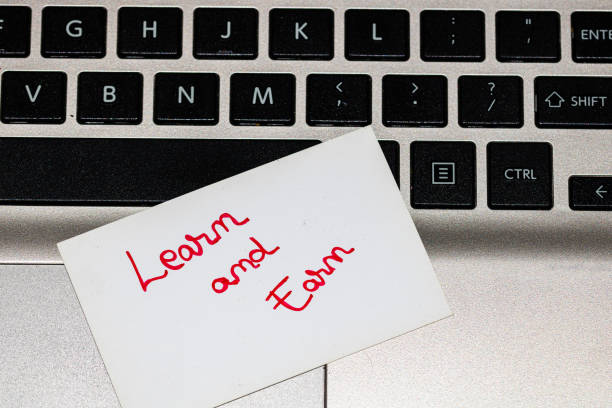 Writing on white label Learn and Earn. Text with Learn and Earn on a label on keyboard.