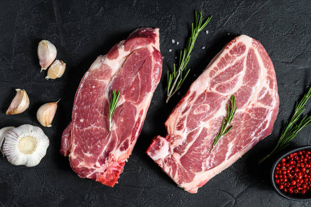 istock Raw pork steak on the bone. Grilled meat. Black background. Top view 1193277988