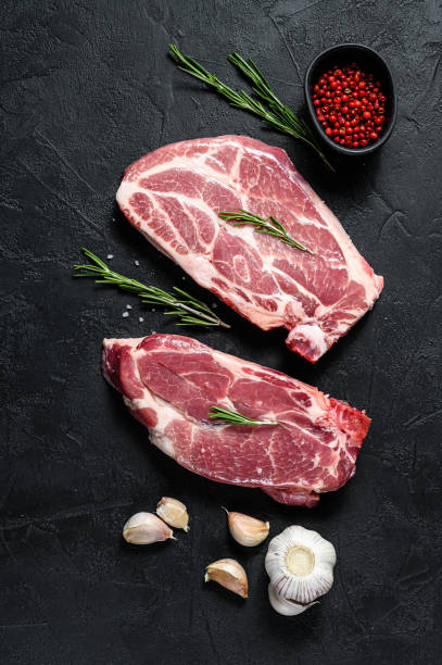 istock Raw pork steak on the bone. Grilled meat. Black background. Top view 1193278040