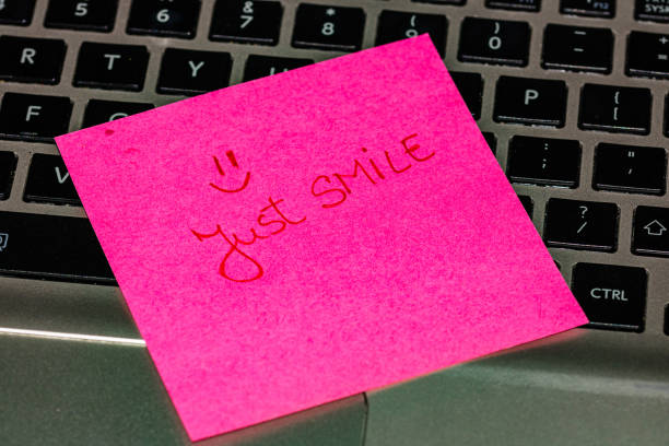 istock Writing on colorful sticky note Just smile. Text with just smile on paper. Sticky note, post it on keyboard. 1193278048