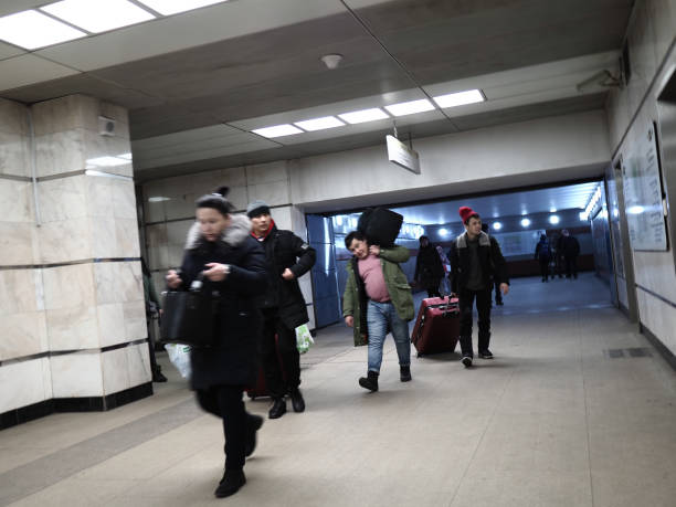 Moscow, Russia - December 08, 2019: Asian passengers are carrying heavy luggage in the underpass of Kotelniki metro station in the night