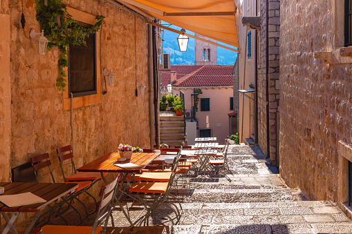 Medieval street with stairs and cafe tables in famous european city of Dubrovnik on a sunny day.