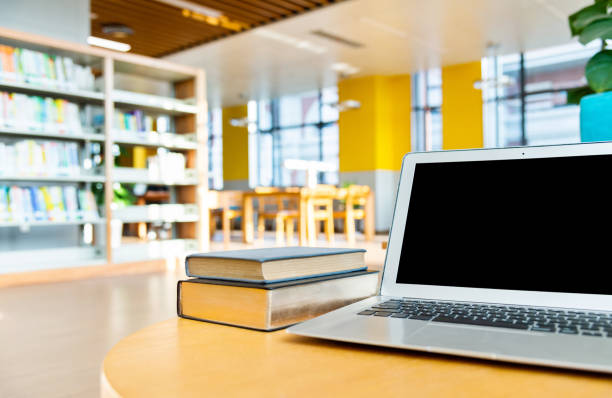 istock Laptop and books on the table of public library 1193279619