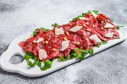 Carpaccio made of raw marbled beef. Gray background. Top view.