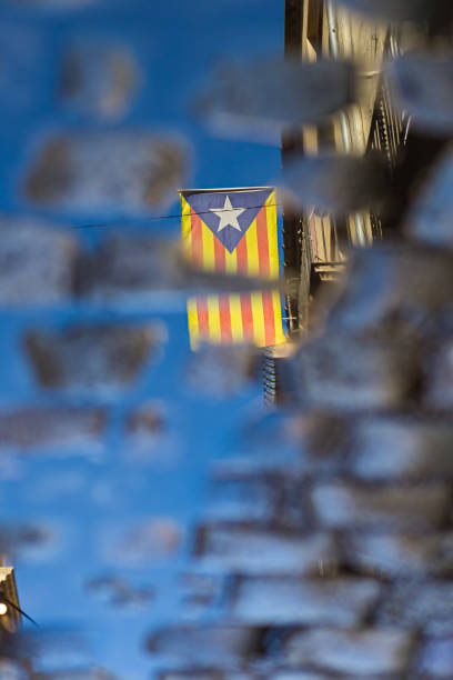 Pro independence Catalan flag symbol reflected on a water pond on a cobble stone street