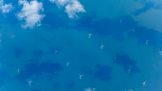 An aerial view of clouds and an offshore wind farm sited in the English Channel, just off the south coast of the UK, seen from an aero plane window whilst flying to London, England.