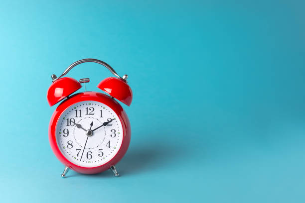 istock red alarm clock on a blue paper background with place for your text 1193286038