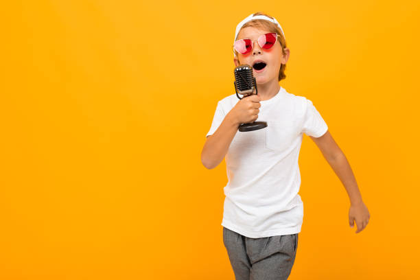 istock blond boy sings into a microphone on an orange background 1193286857