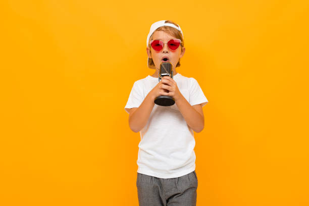 istock blond boy sings into a microphone on a yellow background 1193286858