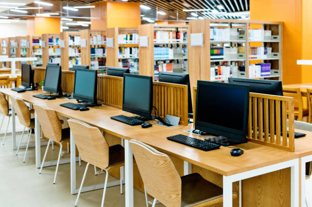computadora y estanterías en la biblioteca moderna - school library fotografías e imágenes de stock