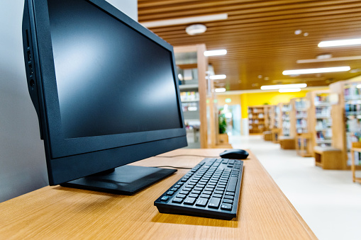 Computer and bookshelves in modern library.