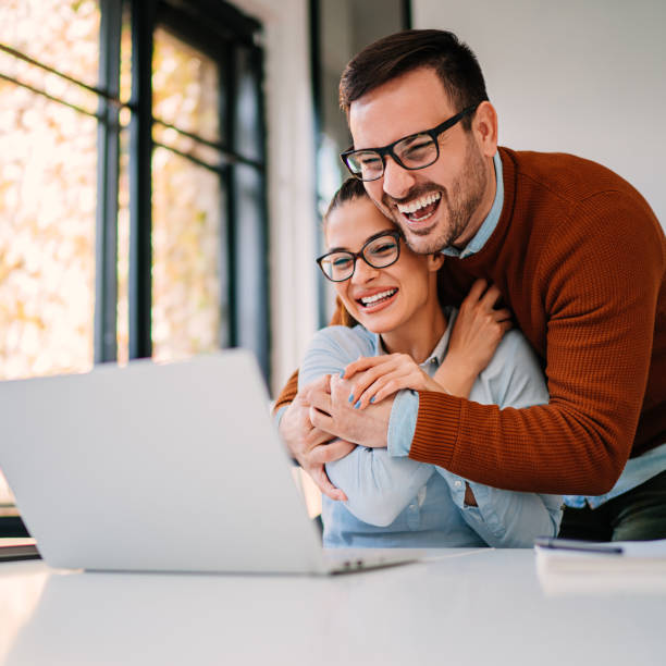 jeunes couples heureux ayant l'appel vidéo de famille - colleague looking at camera indoors lifestyles photos et images de collection