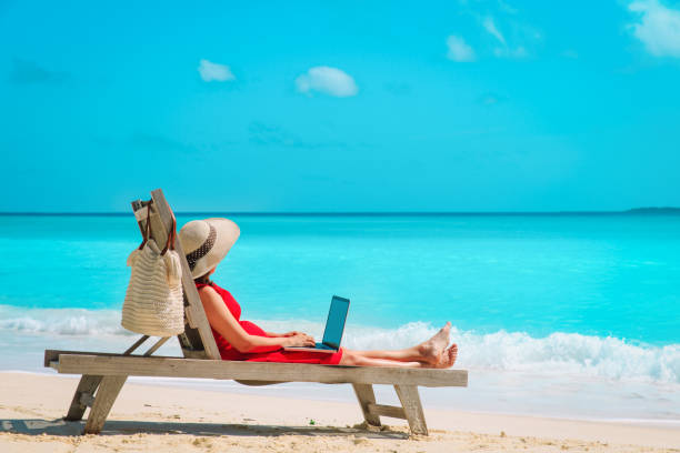 istock remote work concept -young woman with laptop on beach 1193290133