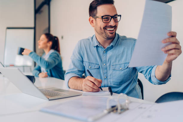 istock Young happy businessman reading contract and writing notes 1193290264