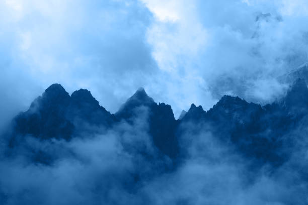 Blue toned landscape of dark rocky mountain ridge silhouette in foggy clouds, High Tatra mountains