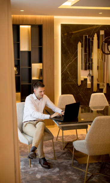 istock Young man sitting in a luxurious room in front of a laptop computer 1193292064