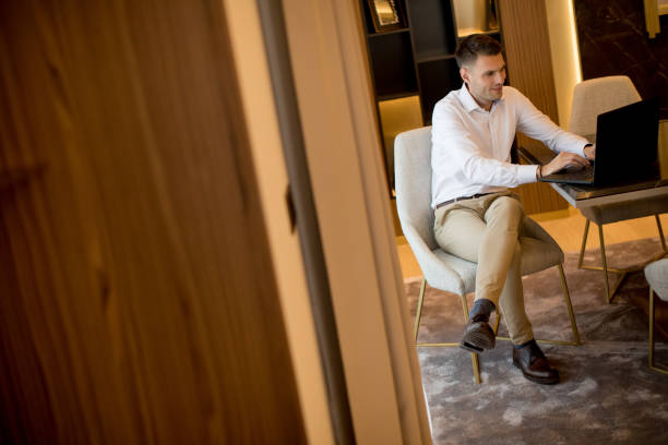 istock Young man sitting in a luxurious room in front of a laptop computer 1193293204