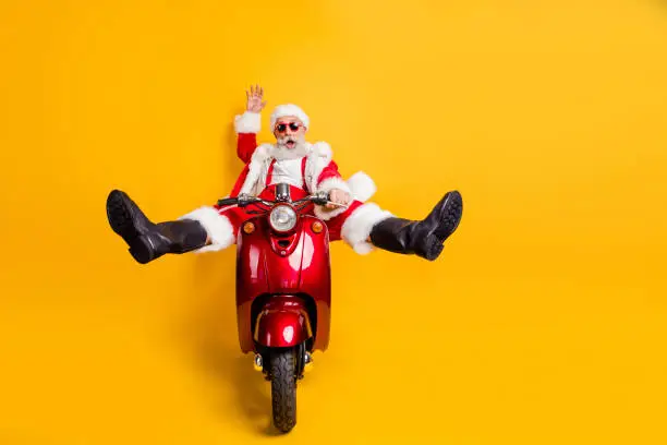 Full size photo of surprised crazy santa claus hipster in red hat shirt suspenders, drive fast motorcycle hurry from north-pole celebrate x-mas christmas party isolated yellow color background