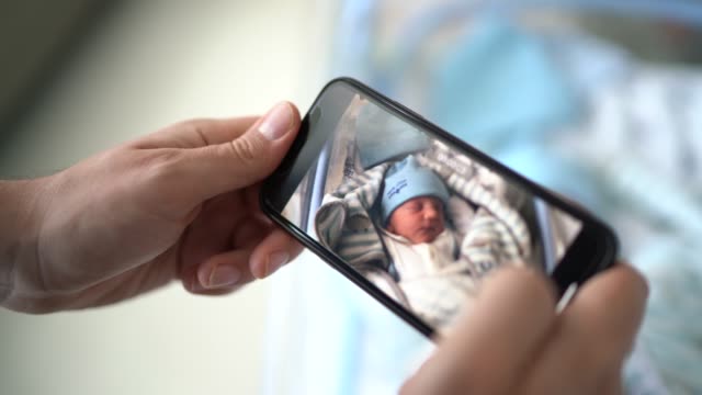 Father taking pictures of his newborn at hospital