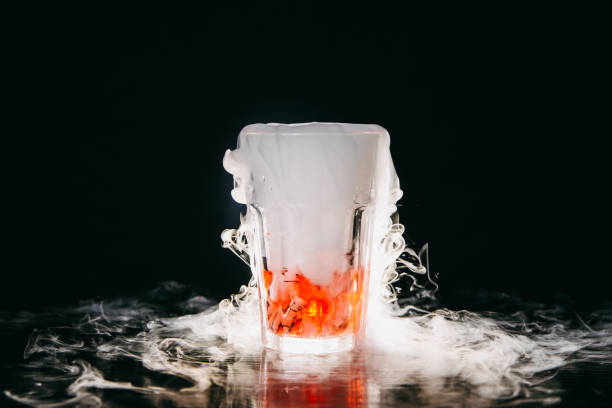 cocktail fumante arancione su sfondo nero - dry ice foto e immagini stock