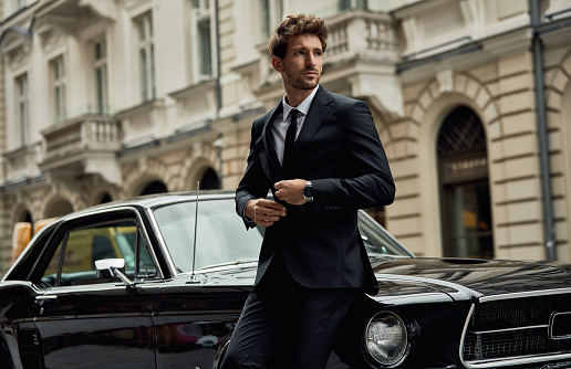 Young handsome man with black classic car wear black suit